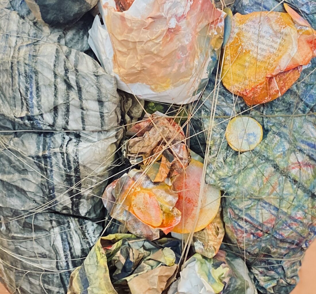 a ball of paper, wrapped and squeezed together, showing bilateral black and multicolour marks on paper.